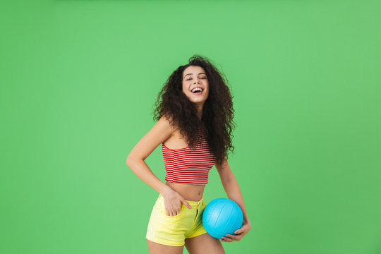 Image of young woman 20s wearing summer clothes smiling and holding volley ball