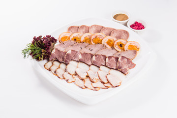 Five types of meat sliced on a plate on a white background with sauces