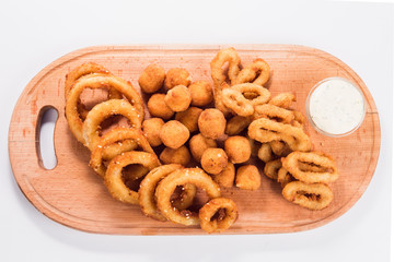 Onion rings and cheese balls with sauce on a wooden board on a white background