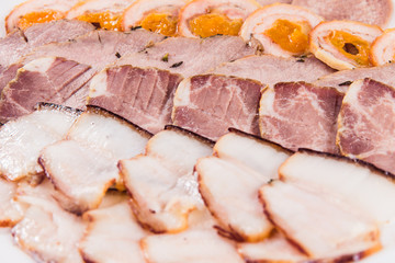Five types of meat sliced on a plate on a white background with sauces