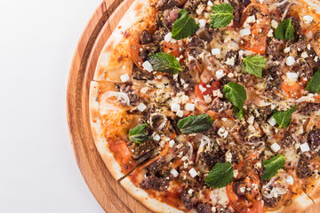 Pizza with mint on a wooden circular board isolated on white background