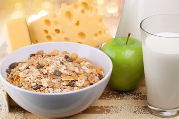Raw oats in bowl and fruit salad, apples on the wooden table