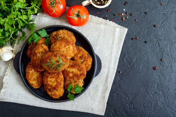 Juicy homemade cutlets (beef, pork, chicken) on a black background. The top view