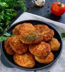 Juicy homemade cutlets (beef, pork, chicken) on a black background.