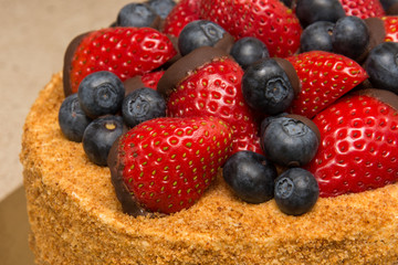 A home made honey cake with strawberries and blueberries on top