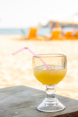 Verre de jus de fruits avec paille à la plage