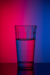 vertical image glass of water on blue pink background