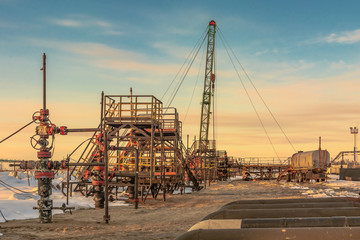 Oil field in Siberia. In a row there are oil producing wells. In the background, work is underway...