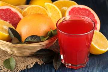 Citrus fruit. Various citrus fruits with leaves of lemon, orange, grapefruit in a basket and grapefruit juice on a blue wooden table.