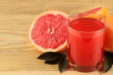 Citrus fruit. Fresh grapefruit with leaves and juice on a natural wooden table. close-up