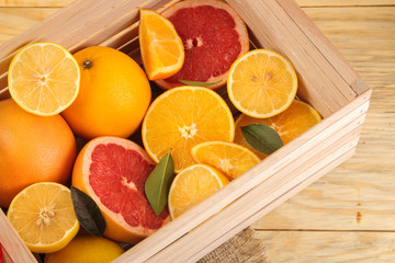 Citrus fruit. various citrus fruits with leaves of lemon, orange, grapefruit in a box on a natural wooden table.