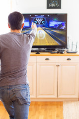 Fototapeta na wymiar A man playing video game without joystick at home. Cheerful father with family playing bowling and having fun with new trends technology. Gaming concept