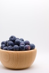 Side view of wooden bowl full of ripe juicy blueberries in wooden bowl isolated on white background with plenty of copyspace