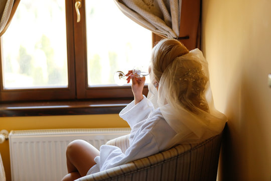 Beautiful bride drick champagne in hotel room