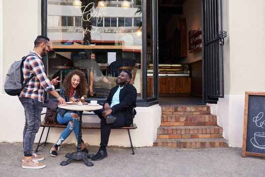 Group Of Smiling Friends Talking Together At A Sidewalk Cafe