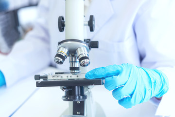 Scientists analyzing study data and evaluating microscope.  Health care researchers doing some research with dropper chemical testing and working in life science laboratory.