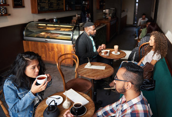 Multiethnic crowd sitting at tables in a trendy cafe