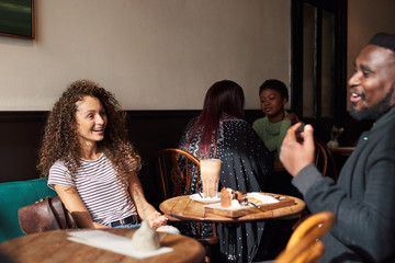 Two diverse friends talking together over coffee in a cafe