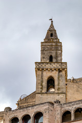Fototapeta na wymiar Church tower and roof with religious cross of Chiesa di Sant'Agostino, view of ancient town of Matera, Basilicata, Southern Italy, cloudy summer warm August day