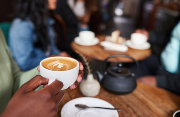 Young woman drinking cappuccino while sitting in a cafe