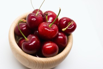 Cherries in wooden bowl isolated on white
