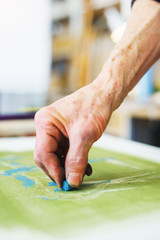 Artist makes the first srihi on canvas in the process of drawing with pastel crayons.