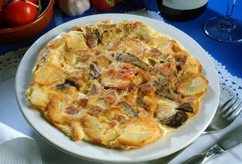 Plato con una tortilla de huevo, patatas, butifarra y jamón.