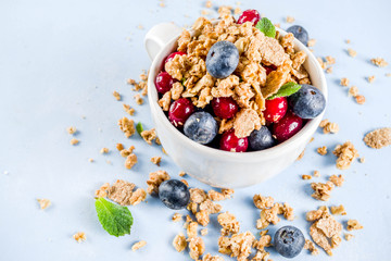Small cup with breakfast oat granola, cereal muesli, nuts and berries. Healthy breakfast or snack concept, Bright trendy background, Top view copy space