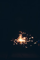 Fototapeta premium sparkling Bengal sparklers sticks in flames on a black background with lights bokeh. christmas theme new year background. holiday card