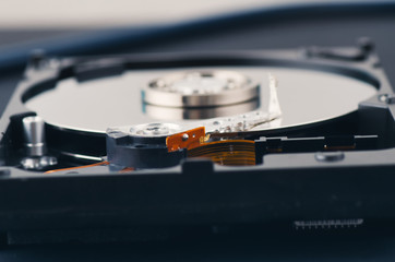 Technology and data recovery concept, stethoscope on old dusty disassembled hard drive from the computer over dark background