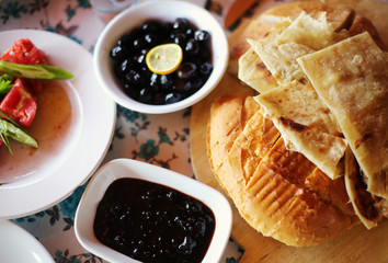 Turkish traditional breakfast with village freshly baked bread, jam, olives. Flat lay top view. 