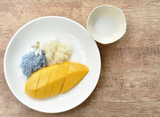 ripen mango with white and purple sticky rice dressing coconut milk on plate