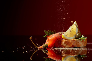 Sandwich with trout fillet, lemon slice, capers and rosemary sprinkle with pepper.