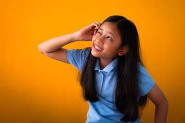 Portrait of funny cute girl thinking isolated on orange background. - 257673680