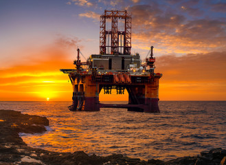 Offshore drilling in rocky coasts of the ocean at the time of the rising of the Sun