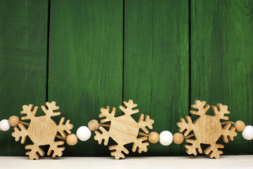 Christmas decoration on the green vintage background. Wooden snowflakes. New year greeting card template.