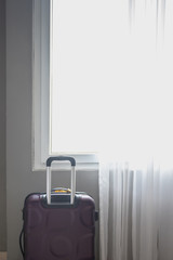 Traveling suitcase on window curtain background in the bedroom.
