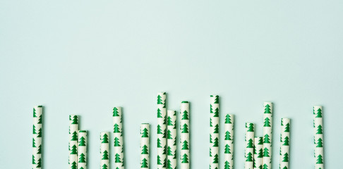 A pile of straws with Christmas trees image on a pastel background. Festive New year  long wide banner with copy space.