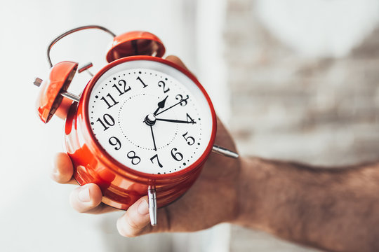 Closeup of a caucasian man adjusting the time of a clock - you can not oversleep or miss important affairs and events
