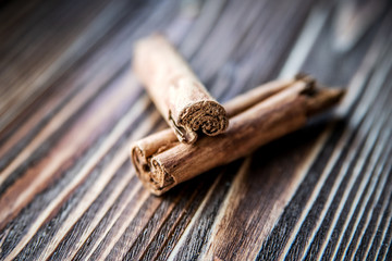 Two cinnamon sticks on a wooden surface.