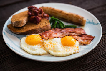 Typial breakfast with eggs, bacon and sausage on plate