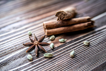 Cardamom, star anise and cinnamon on a wooden surface.