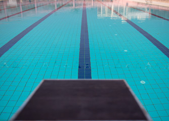 Obraz premium Starting blocks in row by the swimming pool, selective focus. Jump platform for swimming in swimming pool and grandstand background. Swimming pool with starting blocks. Sport facility. 