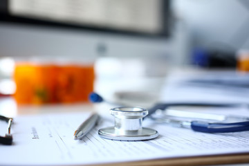 Stethoscope head and silver pen lying on medical application form