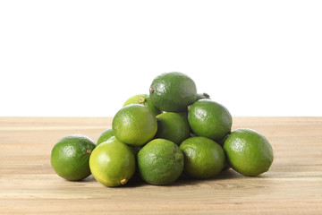 bunch of lime on a wooden table with white background and copy space for your text