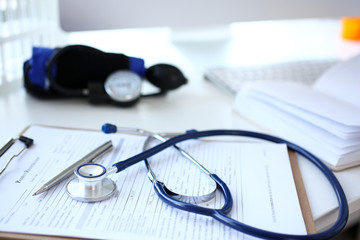 Stethoscope head and silver pen lying on medical application form