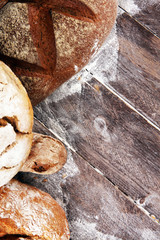 Different kinds of bread and bread rolls on board from above. Kitchen or bakery