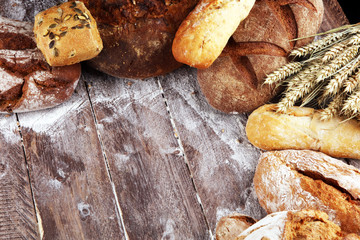 Different kinds of bread and bread rolls on board from above. Kitchen or bakery