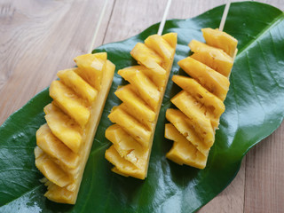 Sliced pineapple fruit on top of the background wood