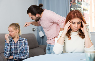 Mature woman sitting, man and girl having conflict on background